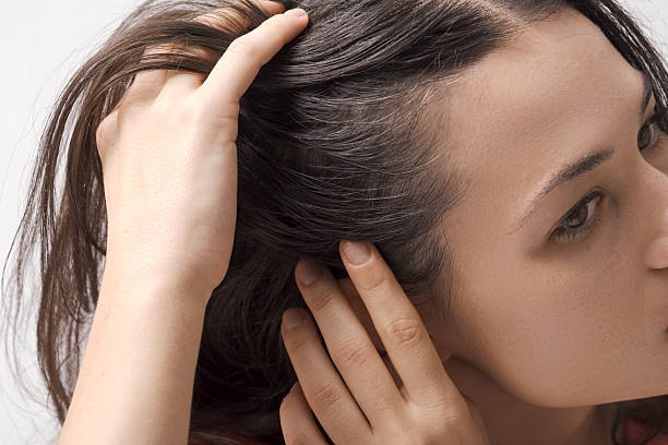 Young worried woman checking her hair and scalp, hair care concept